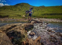 Cyclist carrying over river crossing in Glen Lyon  - part of the West Coast Cycle Trail